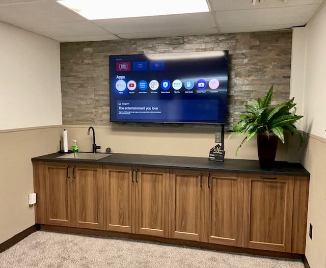 Conference room with wall-mounted presentation screen, sink, and built-in wood cabinetry