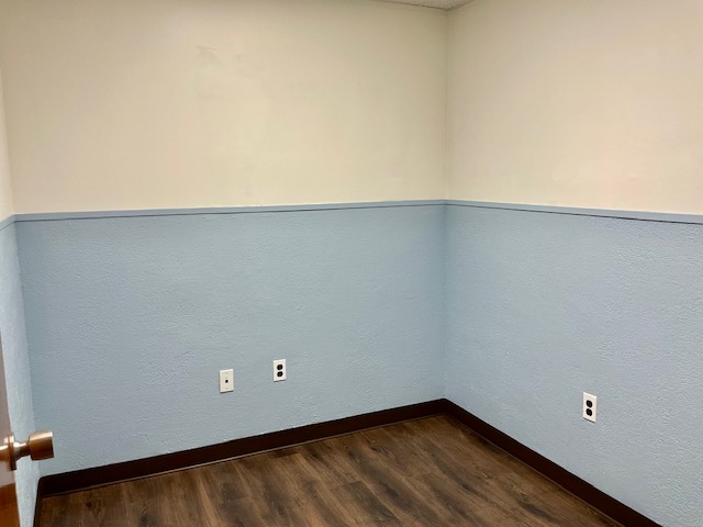 Vacant private suite with two-tone blue and cream walls and dark luxury plank vinyl flooring, ready for tenant buildout