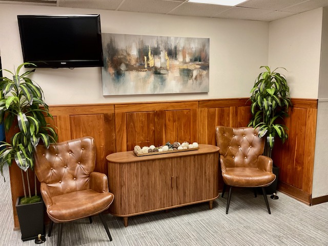 Sitting room lounge with two leather wingback chairs, a wall-mounted TV, and abstract artwork